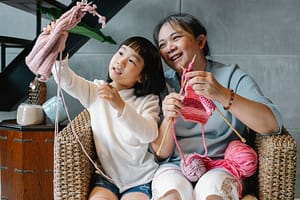 charming girl with grandmother and knitting